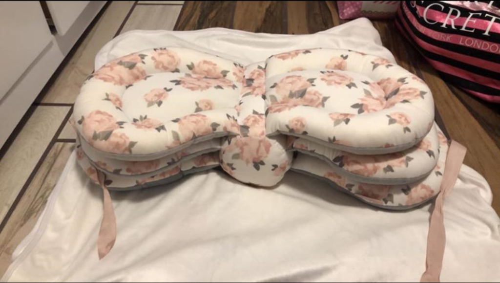 A baby's headrest with a pink flower pattern, shown in use with The Pharmedoc Nursing Pillow for a product review.